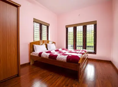 a bedroom with a bed and two windows at Haven inn in Kotagiri