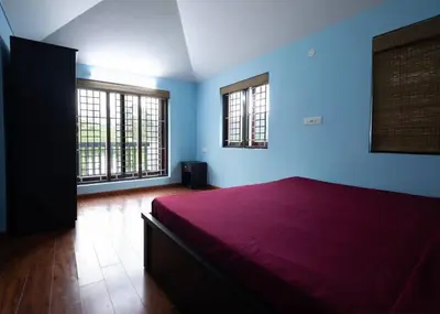 a bedroom with a purple bed and two windows at Haven inn in Kotagiri