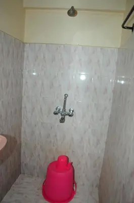 a pink container sitting on the floor of a shower at Bethany stay in Ooty