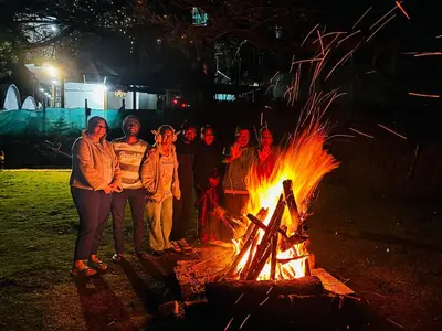 a group of people standing around a fire at night at Sunrise Peak View in Lovedale