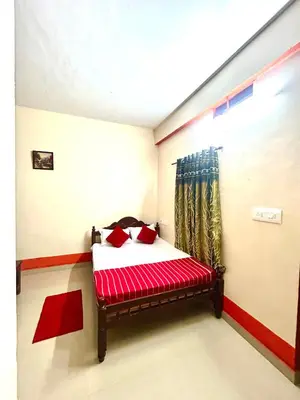 a bedroom with a bed with red sheets and a window at GV Royal Residency Vattavada in Vattavada