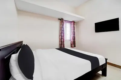 a bedroom with a black and white bed and a television at Super Hotel O Viswapuram in Coimbatore