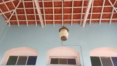 a light fixture hanging from the ceiling of a room with two windows at Cliff Club Resort Ooty in Ooty