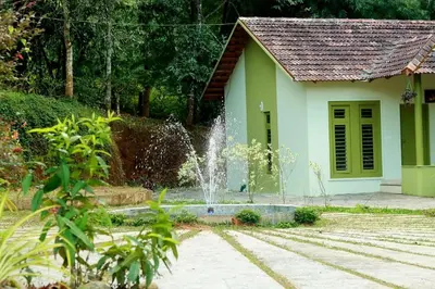 a small house with a fountain in front of it at Ayurnest Pool Resort Wayanad in Batheri