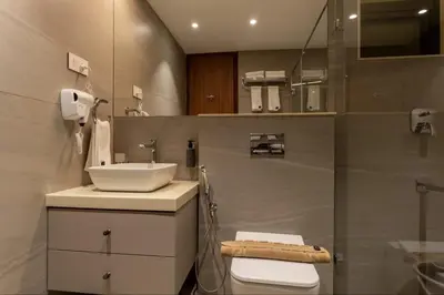 a bathroom with a sink and a toilet and a mirror at Seashell Apartments in Kozhikode