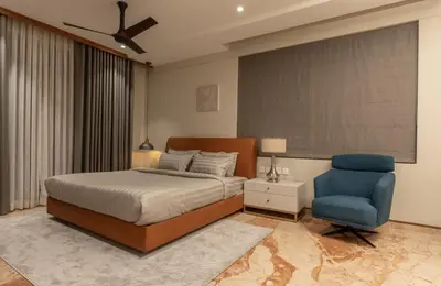 a bedroom with a bed and a blue chair at Seashell Apartments in Kozhikode