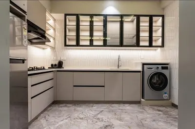 a kitchen with white cabinets and a washer and dryer at Seashell Apartments in Kozhikode