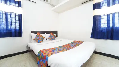 a bedroom with two beds and blue curtains at Codissia In Nini Residency in Coimbatore