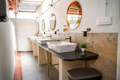 a bathroom with a row of sinks and mirrors at Leo Vishroam in Mysore