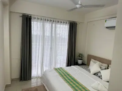 a bedroom with a bed and a large window at Memmsta Blooming Bird Guruvayur in Guruvāyūr