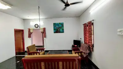 a living room with a ceiling fan and chairs at NJM Villa in Coimbatore