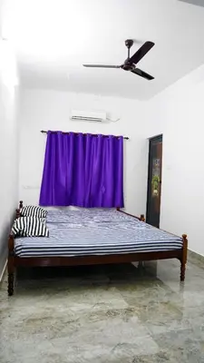a bed in a room with a purple curtain at Prakruthi Home stay in Kanjikode