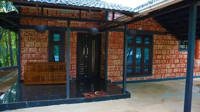 a house with a red brick wall with a black door at Prakruthi Home stay in Kanjikode