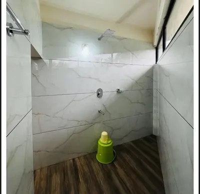 a shower with white marble walls and a green container at Sara Archid in Kommeri