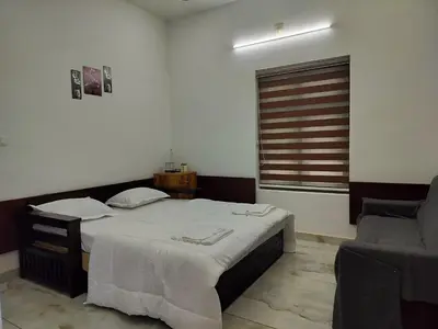 a bedroom with a large bed and a chair at Roneys Villa in Wayanad