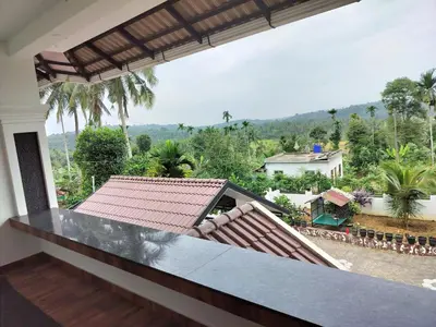 a balcony with a view of a house at Roneys Villa in Wayanad