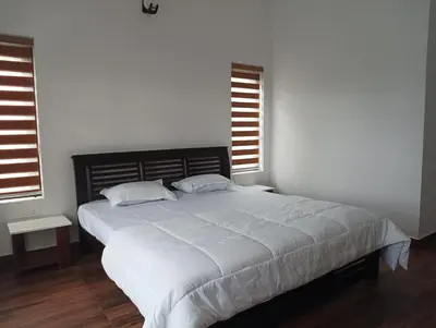 a bedroom with a large white bed with two pillows at Roneys Villa in Wayanad