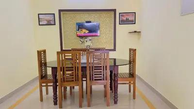a dining room table and chairs with a tv on the wall at Golden pearl private villa with pool in Vythiri