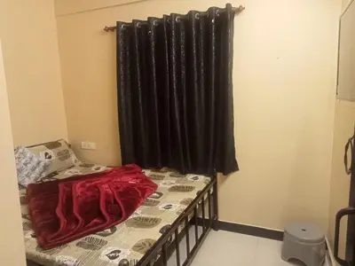 a room with a bed and a black curtain at HRS Budget Rooms in Ooty