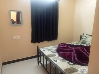 a small room with a bed and a mirror at HRS Budget Rooms in Ooty