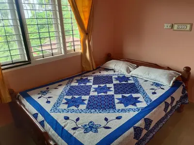 a bedroom with a blue and white quilt on a bed at Abiraksha Stay Coorg in Madikeri
