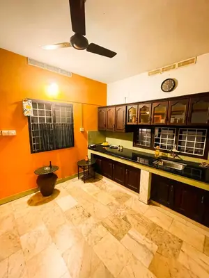 a large kitchen with orange walls and wooden cabinets at Boughn Villa in Kozhikode