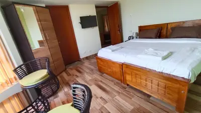 a bedroom with a bed and chairs and a balcony at Dwarka Home Stay in Ooty