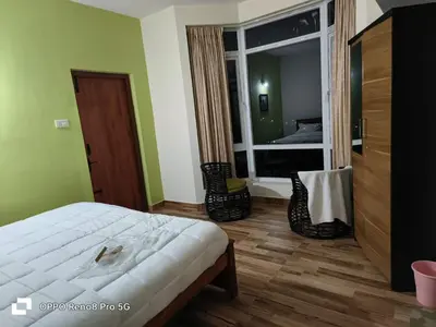 a bedroom with a bed and a large window with a bed sidx sidx at Dwarka Home Stay in Ooty