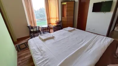 a bedroom with a white bed and a large window at Dwarka Home Stay in Ooty