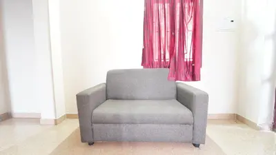a gray chair in a room with a window at Hotel Varun 1 bhk in Coimbatore