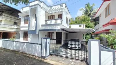 a white house with a black fence at Moms Villa in Nedumbassery