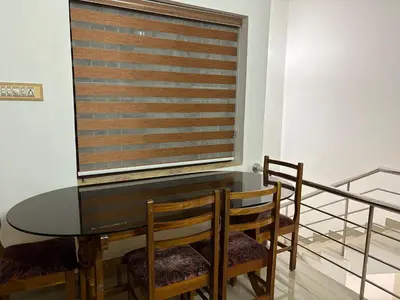 a dining room with a glass table and chairs at Moms Villa in Nedumbassery