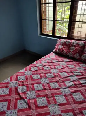 a quilt on a bed in a room with a window at Beautiful and Peaceful house in Kanjikode