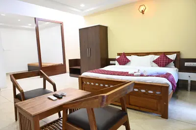 a bedroom with a bed and a table and a chair at Hotel Aamis Villa in Pulpally