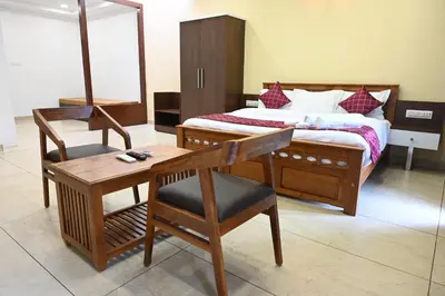 a bedroom with a bed with a desk and a chair at Hotel Aamis Villa in Pulpally