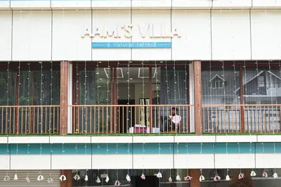 a person standing on a balcony in front of a building at Hotel Aamis Villa in Pulpally