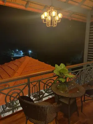 a table and chairs on a balcony with a chandelier at The Elegant homes in Kushālnagar