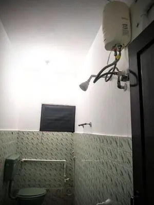 a bathroom with a toilet and a light on the wall at Mithu's Nest-Ur Holiday Abode in Coimbatore