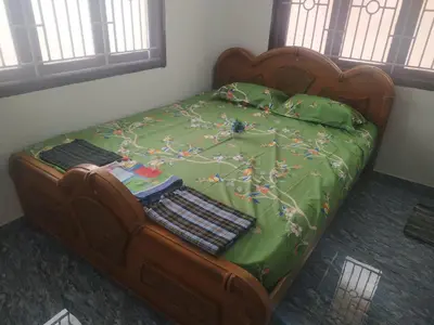 a bed with a green comforter with two bags on it at Mithu's Nest-Ur Holiday Abode in Coimbatore