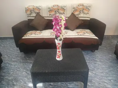 a vase with flowers on a table in front of a couch at Mithu's Nest-Ur Holiday Abode in Coimbatore