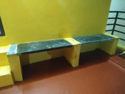 a bench sitting against a yellow wall at Mithu's Nest-Ur Holiday Abode in Coimbatore