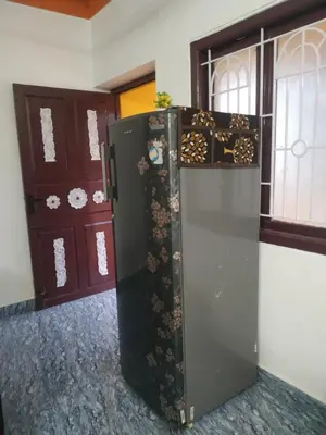 a black refrigerator in a room next to some doors at Mithu's Nest-Ur Holiday Abode in Coimbatore