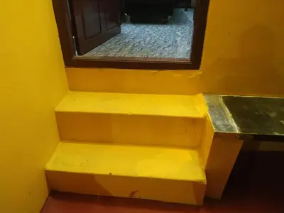 a yellow staircase with a window in a yellow wall at Mithu's Nest-Ur Holiday Abode in Coimbatore