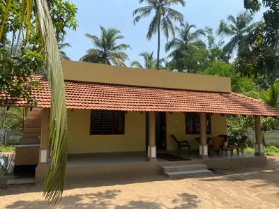 a small yellow house with a red roof at Gaya beach hacienda in Irimbranallūr