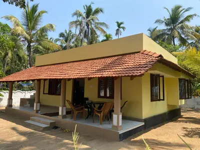a small yellow house with a table and chairs at Gaya beach hacienda in Irimbranallūr