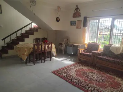 a living room with a table and chairs and a staircase at Ooty mountain cottage in Ooty