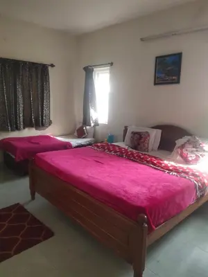 two beds in a bedroom with pink sheets at Ooty mountain cottage in Ooty