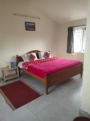 a bedroom with a wooden bed with a red blanket at Ooty mountain cottage in Ooty