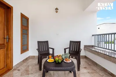 two chairs and a table with fruit on a balcony at Stayvista at Whitewood Serene 5BHK Homestay - Wayanad in Wayanad
