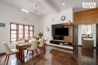 a dining room with a table and chairs and a television at Stayvista at Whitewood Serene 5BHK Homestay - Wayanad in Wayanad